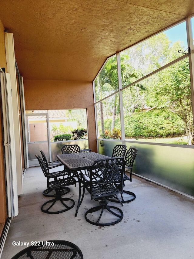 sunroom / solarium featuring a healthy amount of sunlight and vaulted ceiling