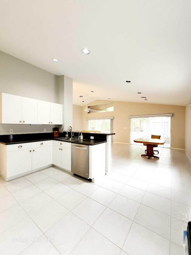 kitchen with sink, vaulted ceiling, light tile patterned floors, stainless steel dishwasher, and white cabinets