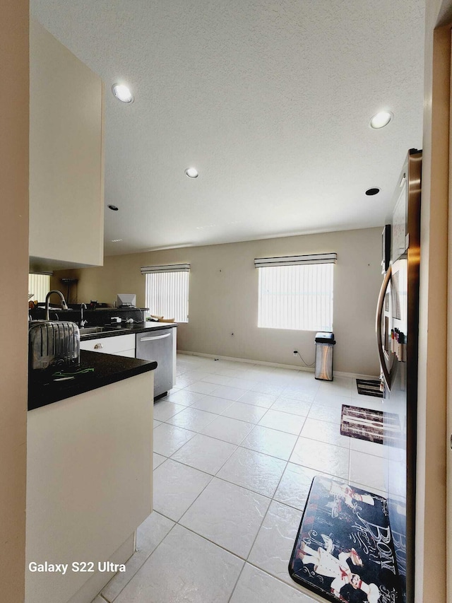 kitchen featuring light tile patterned flooring, stainless steel dishwasher, and a textured ceiling