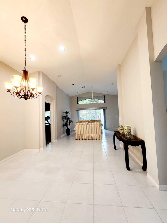 hallway featuring light tile patterned floors, a notable chandelier, and vaulted ceiling