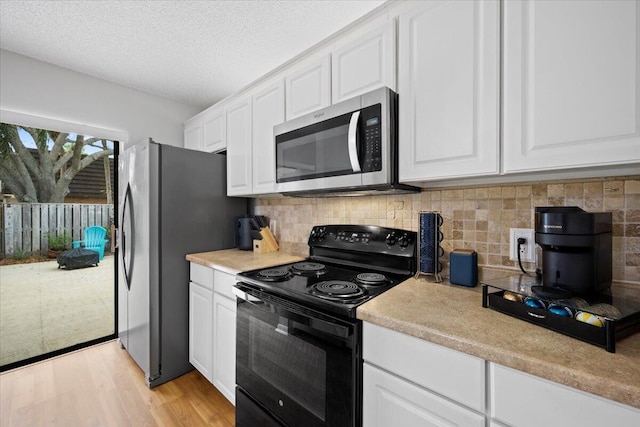 kitchen featuring light wood-type flooring, backsplash, a textured ceiling, stainless steel appliances, and white cabinets