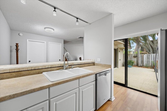 kitchen with appliances with stainless steel finishes, light wood-type flooring, a textured ceiling, sink, and white cabinetry