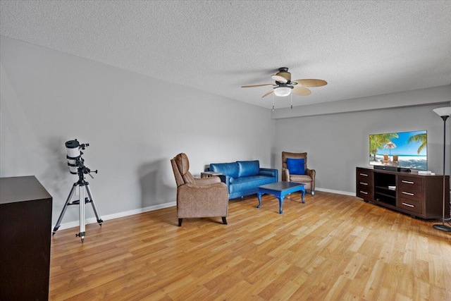 living area with a textured ceiling, light hardwood / wood-style flooring, and ceiling fan