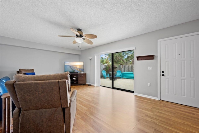 living room with ceiling fan, light hardwood / wood-style floors, and a textured ceiling