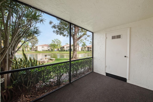 unfurnished sunroom featuring a water view