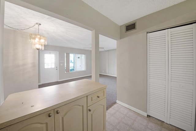 kitchen featuring a textured ceiling, pendant lighting, cream cabinetry, and a notable chandelier