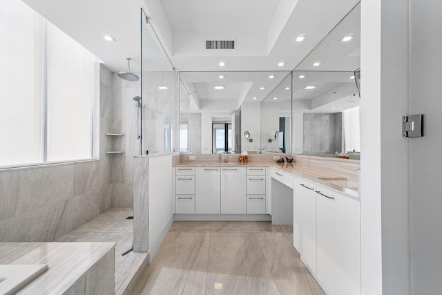 bathroom featuring tiled shower, vanity, and plenty of natural light