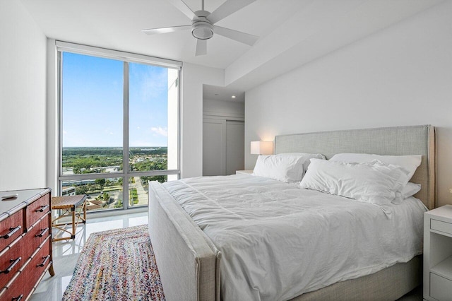 bedroom with multiple windows, ceiling fan, and a wall of windows