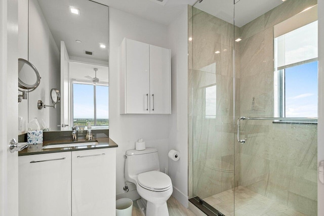 bathroom featuring ceiling fan, toilet, vanity, and walk in shower