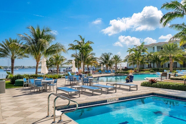 view of swimming pool with a water view, central air condition unit, and a patio