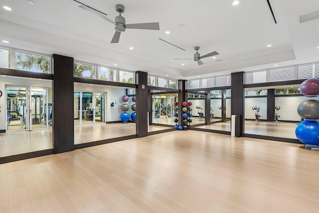 exercise room with ceiling fan, light wood-type flooring, a high ceiling, and french doors