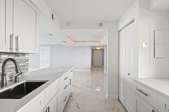 kitchen featuring electric panel, white cabinets, sink, light stone countertops, and tasteful backsplash