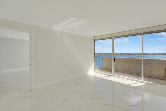 spare room featuring expansive windows, a water view, and ornamental molding