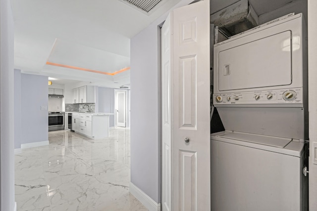 laundry room with stacked washing maching and dryer and sink