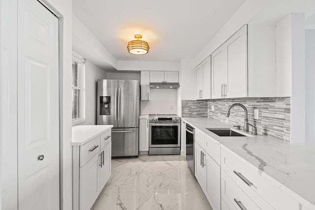 kitchen with backsplash, white cabinets, sink, light stone counters, and stainless steel appliances