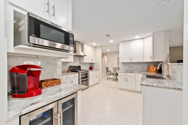 kitchen with white cabinets, appliances with stainless steel finishes, beverage cooler, and wall chimney exhaust hood