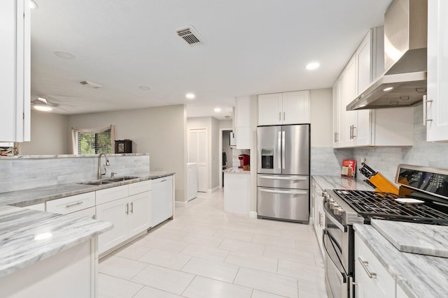 kitchen featuring appliances with stainless steel finishes, sink, white cabinetry, and wall chimney range hood