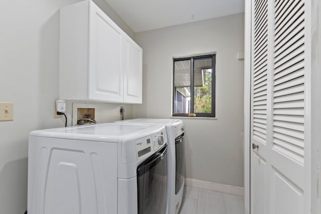 clothes washing area featuring light tile patterned flooring, cabinets, and separate washer and dryer