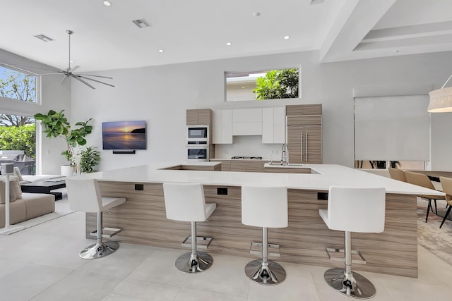 kitchen featuring a breakfast bar, a spacious island, sink, built in appliances, and white cabinetry