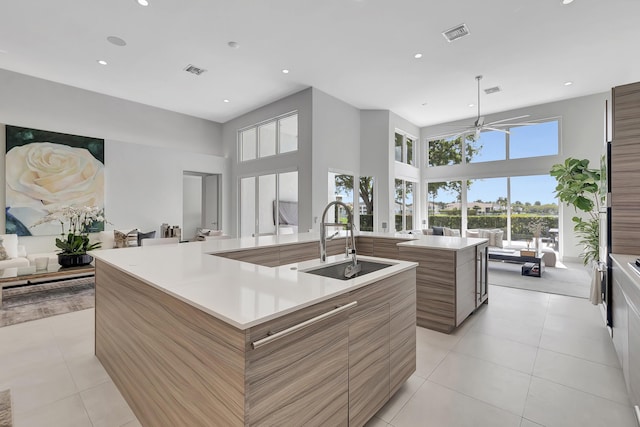 kitchen with light tile patterned flooring, a large island with sink, ceiling fan, and sink