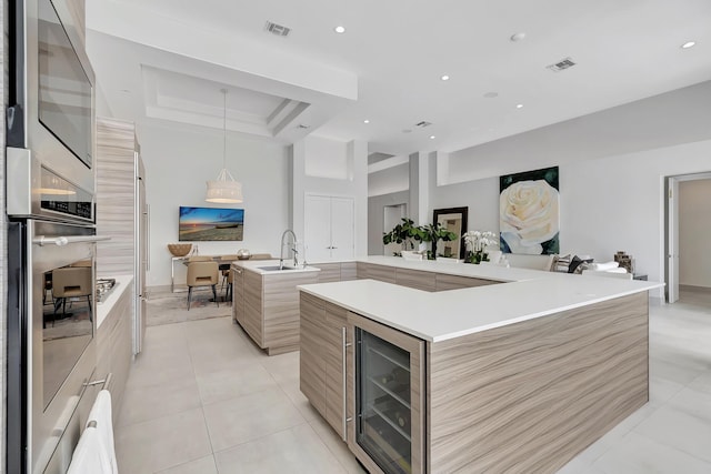 kitchen featuring a large island, beverage cooler, a raised ceiling, light tile patterned floors, and appliances with stainless steel finishes