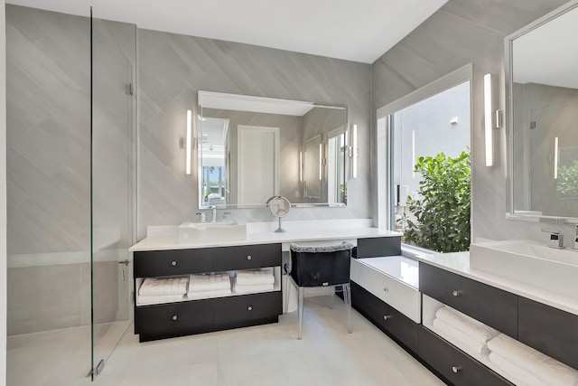 bathroom featuring tile patterned flooring, vanity, a shower with shower door, and tile walls