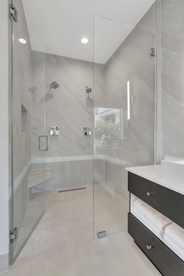 bathroom featuring a shower with door and vanity