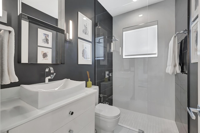 bathroom with a tile shower, vanity, and toilet