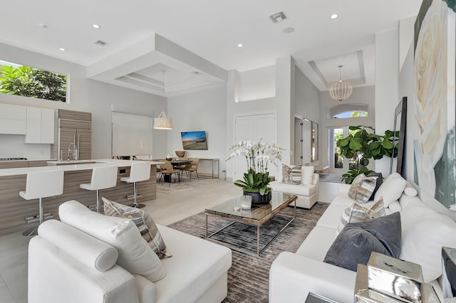 living room featuring a towering ceiling, an inviting chandelier, and sink