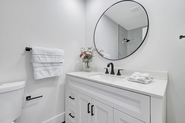 bathroom with a tile shower, vanity, and toilet