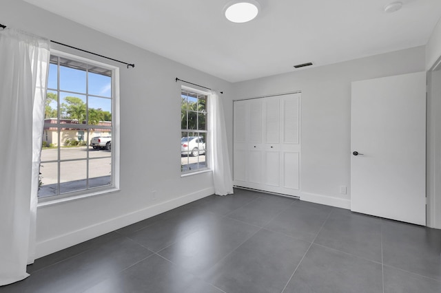 unfurnished bedroom with dark tile patterned floors and a closet