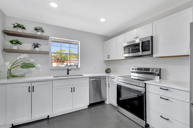 kitchen featuring dark tile patterned floors, sink, white cabinets, and appliances with stainless steel finishes