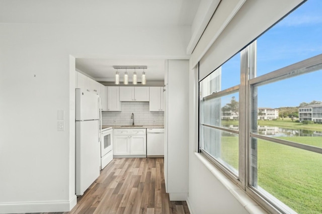 kitchen featuring white cabinetry, sink, tasteful backsplash, white appliances, and a water view