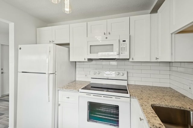 kitchen with backsplash, white cabinetry, light stone counters, and white appliances