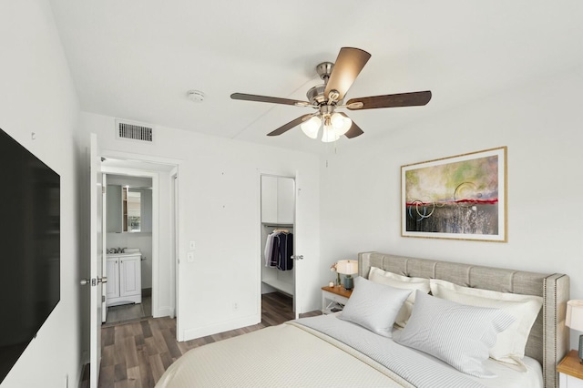 bedroom with a closet, a walk in closet, dark hardwood / wood-style floors, and ceiling fan