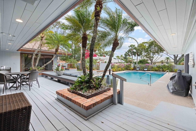 view of swimming pool featuring a wooden deck and a grill