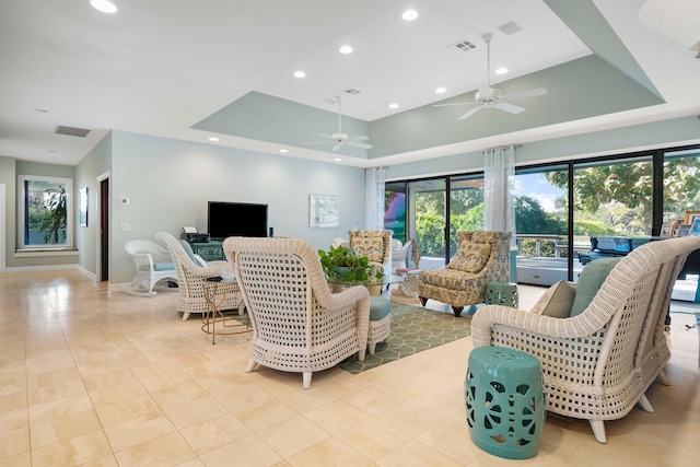 living room featuring ceiling fan, a raised ceiling, light tile patterned floors, and a high ceiling