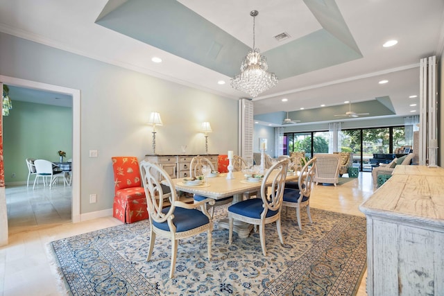 tiled dining area with ceiling fan with notable chandelier, a raised ceiling, and crown molding