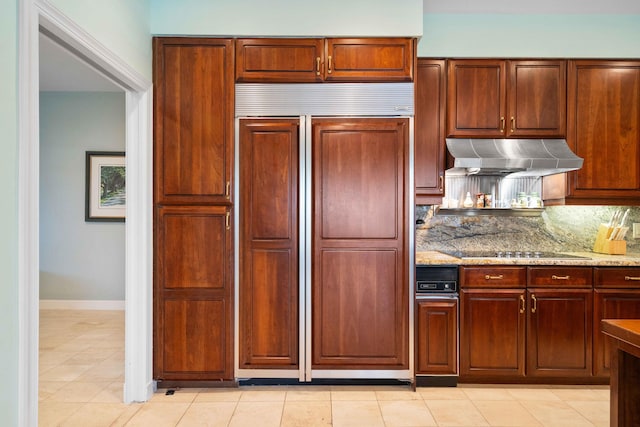 kitchen with decorative backsplash, black electric stovetop, light stone counters, paneled built in fridge, and light tile patterned flooring