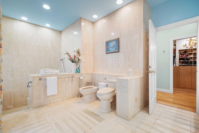 bathroom featuring tile patterned floors, a shower, a bidet, tile walls, and toilet