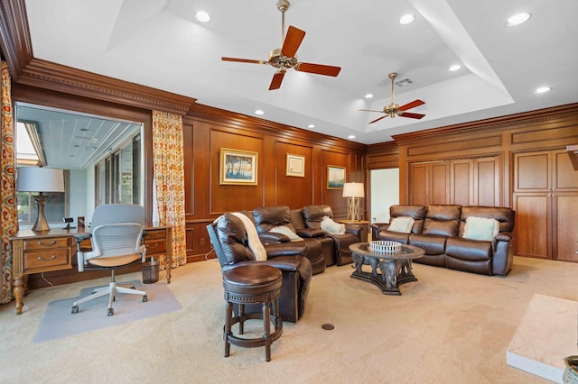 carpeted living room featuring a raised ceiling, ceiling fan, ornamental molding, and wood walls