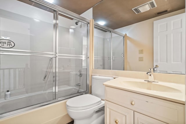 full bathroom with vanity, bath / shower combo with glass door, and toilet