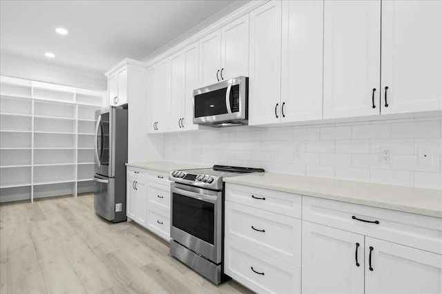 kitchen with light wood finished floors, white cabinets, stainless steel appliances, backsplash, and recessed lighting