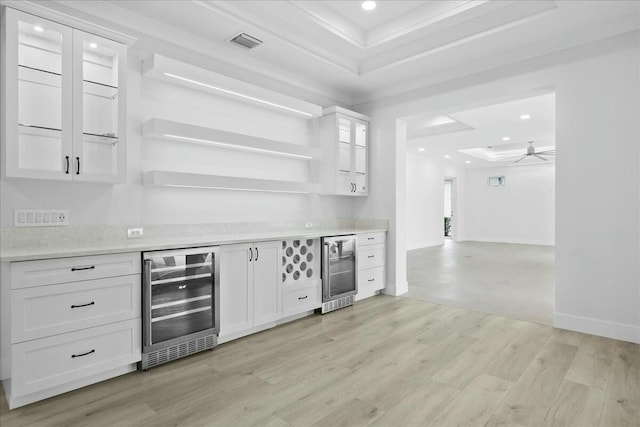 bar featuring a tray ceiling, wine cooler, visible vents, and light wood-style floors