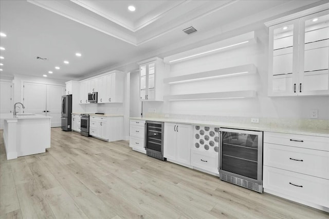 kitchen with beverage cooler, appliances with stainless steel finishes, and light wood-style flooring