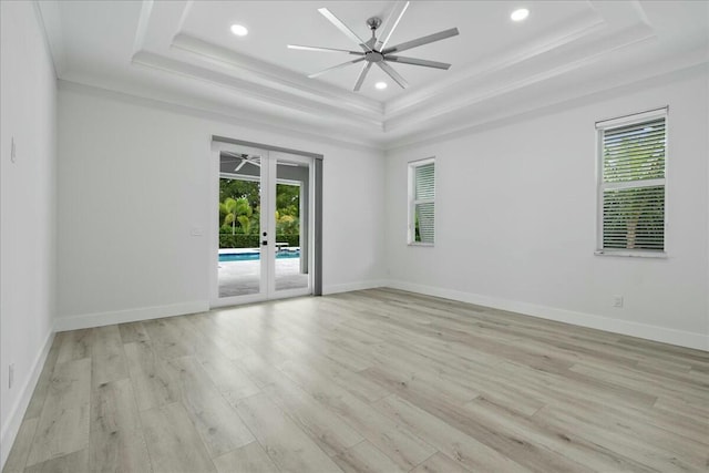 empty room featuring plenty of natural light, a tray ceiling, and french doors