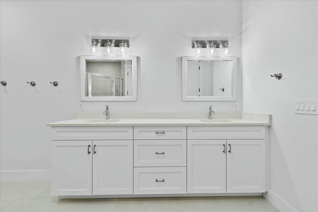 bathroom featuring baseboards, double vanity, a sink, and a shower stall