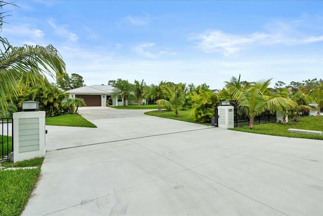 view of front facade featuring an attached garage, driveway, a front lawn, and fence