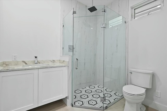 bathroom with toilet, a marble finish shower, and vanity