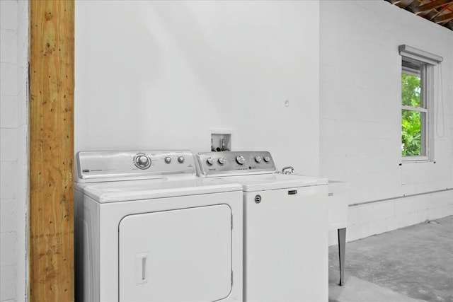 washroom featuring concrete block wall, laundry area, and washing machine and clothes dryer